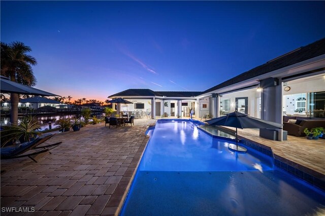 pool at dusk featuring a patio area