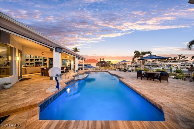 pool at dusk featuring a patio area and a water view