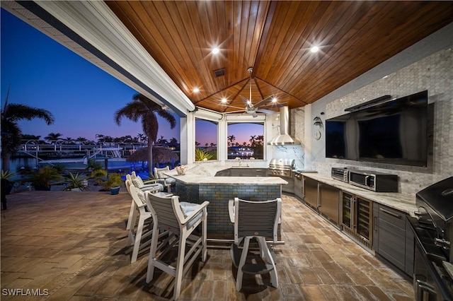 view of patio featuring ceiling fan, a bar, and exterior kitchen