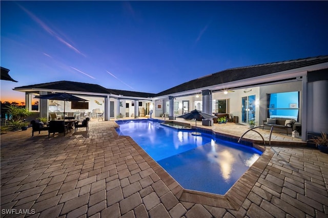 pool at dusk with a jacuzzi and a patio area