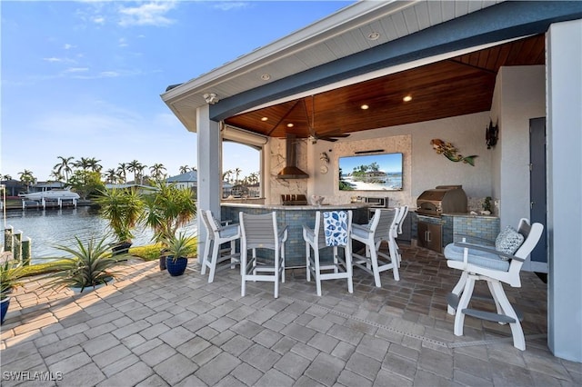 view of patio with exterior bar, a water view, area for grilling, and grilling area