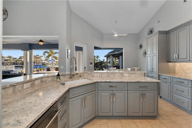 kitchen with light stone counters, ceiling fan, sink, dishwasher, and gray cabinets