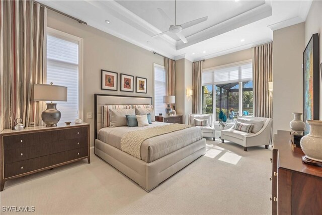 bedroom with ceiling fan, crown molding, light carpet, and a tray ceiling