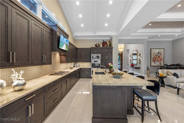 kitchen with light stone countertops, sink, stainless steel appliances, a kitchen breakfast bar, and a kitchen island with sink