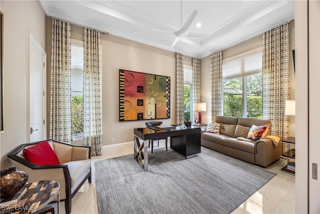 living area with a tray ceiling, ceiling fan, and light tile patterned floors