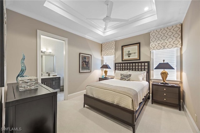 bedroom with light carpet, a raised ceiling, ceiling fan, crown molding, and connected bathroom