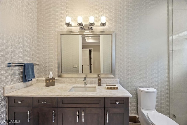 bathroom with vanity, toilet, a shower with shower door, and tile walls