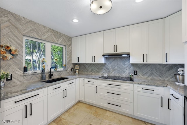 kitchen featuring light stone countertops, black electric stovetop, tasteful backsplash, sink, and white cabinets