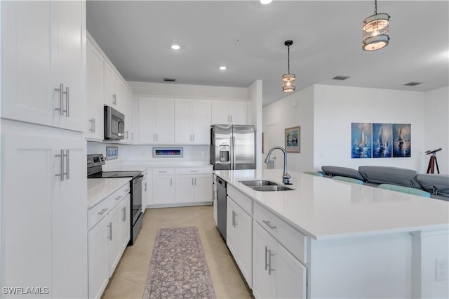 kitchen featuring a center island with sink, sink, appliances with stainless steel finishes, decorative light fixtures, and white cabinetry