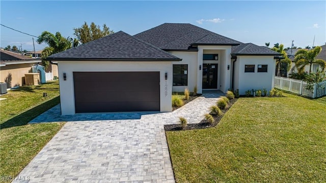 view of front of house featuring central AC, a garage, and a front lawn