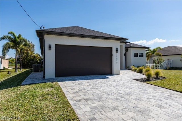 view of front facade featuring a front yard, central AC, and a garage