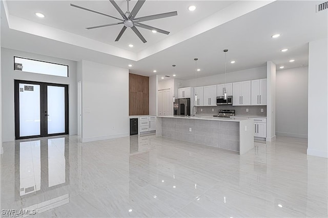 kitchen with appliances with stainless steel finishes, french doors, decorative light fixtures, white cabinetry, and a large island