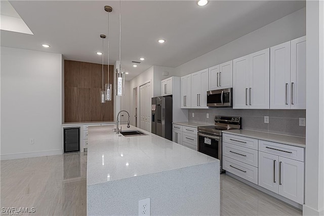 kitchen with appliances with stainless steel finishes, sink, pendant lighting, white cabinets, and wine cooler