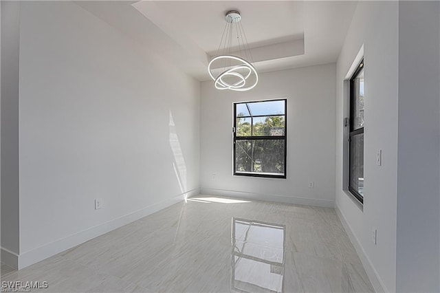 empty room featuring a notable chandelier and a tray ceiling