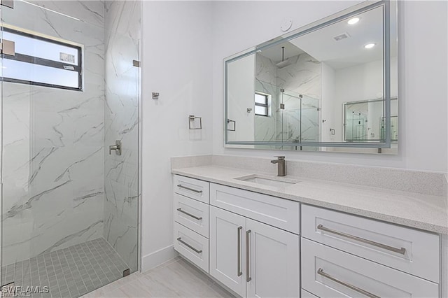 bathroom with vanity, a shower with shower door, and a wealth of natural light