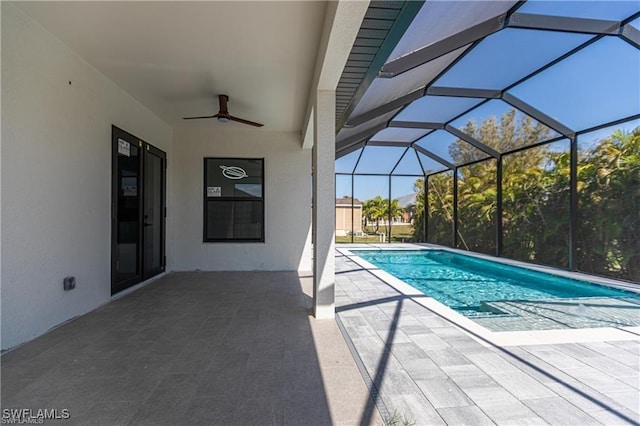 view of pool with a patio, glass enclosure, and ceiling fan