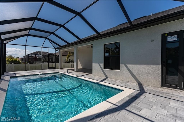 view of swimming pool featuring glass enclosure, ceiling fan, and a patio area