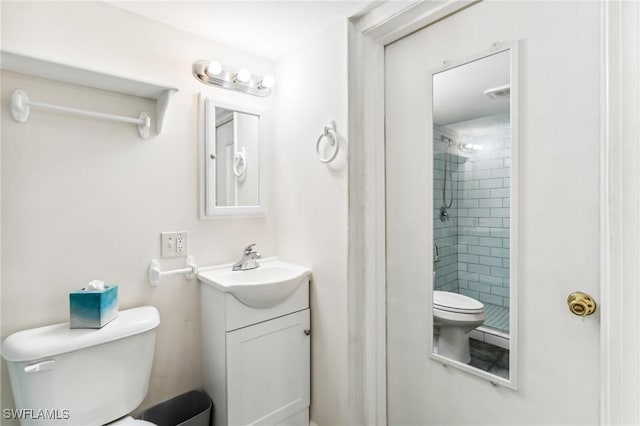 bathroom featuring vanity, toilet, and tiled shower