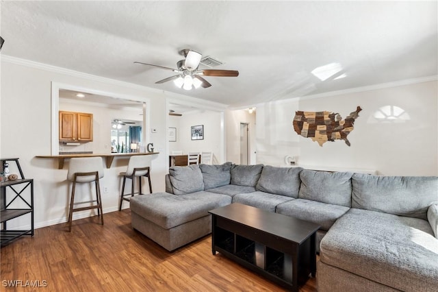 living room featuring ceiling fan, ornamental molding, and wood-type flooring