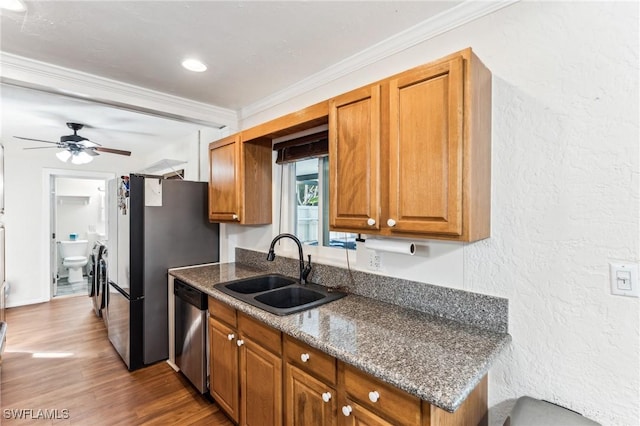 kitchen featuring dark stone countertops, sink, crown molding, and appliances with stainless steel finishes