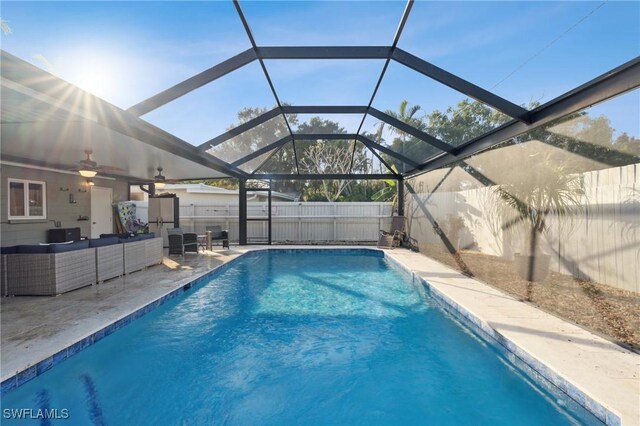 view of swimming pool featuring a lanai, an outdoor living space, ceiling fan, and a patio area