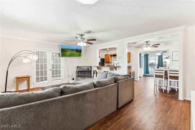 living room featuring ceiling fan, ornamental molding, wood-type flooring, and french doors