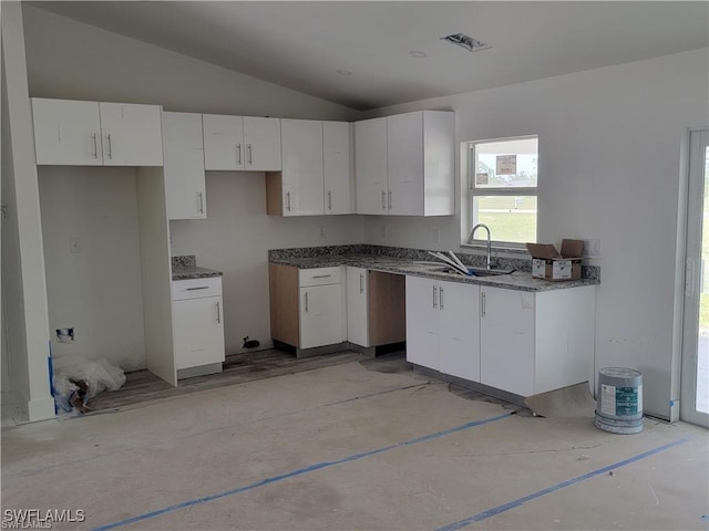 kitchen with white cabinetry, lofted ceiling, and sink