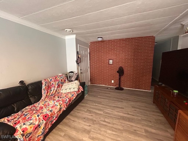 living room with wood-type flooring, crown molding, and brick wall