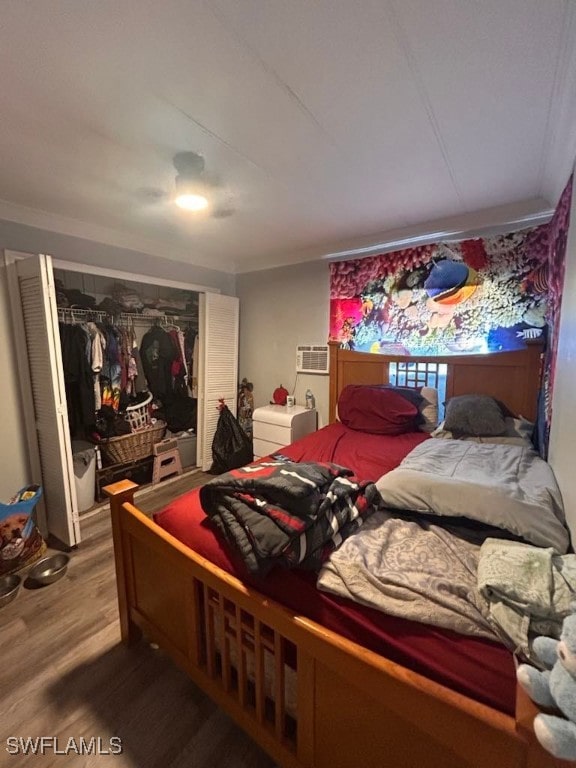 bedroom with hardwood / wood-style floors, ceiling fan, a wall unit AC, and a closet