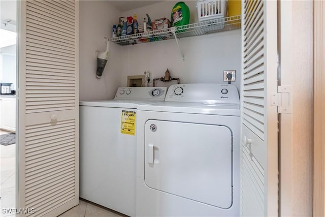 clothes washing area with washer and dryer and light tile patterned floors