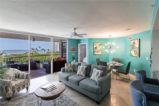 living room featuring ceiling fan with notable chandelier, light tile patterned flooring, a water view, and expansive windows