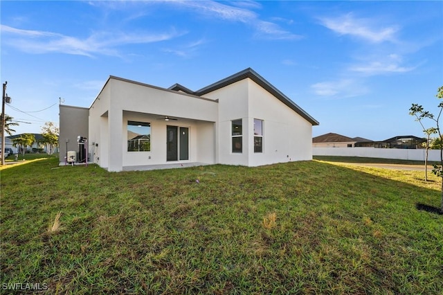 rear view of house with a lawn and ceiling fan