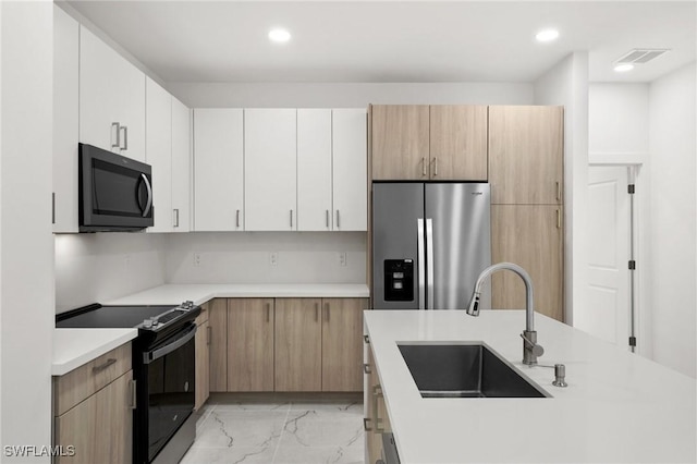 kitchen featuring light brown cabinets, white cabinetry, sink, and appliances with stainless steel finishes