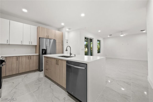 kitchen with ceiling fan, sink, stainless steel appliances, an island with sink, and white cabinets