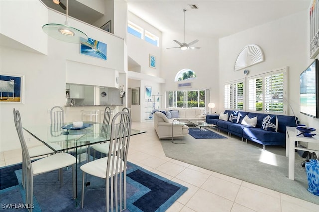 dining area with ceiling fan, light tile patterned flooring, and a high ceiling