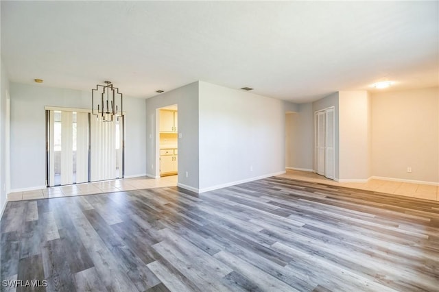 unfurnished living room featuring a chandelier and light hardwood / wood-style floors