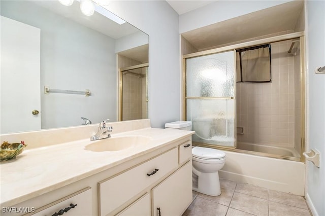 full bathroom with tile patterned flooring, vanity, bath / shower combo with glass door, and toilet