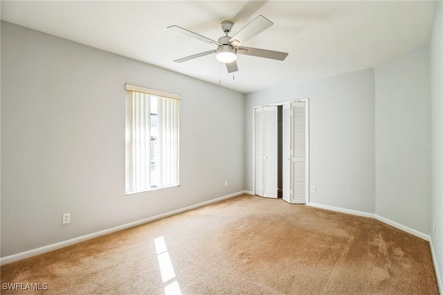 carpeted spare room featuring ceiling fan