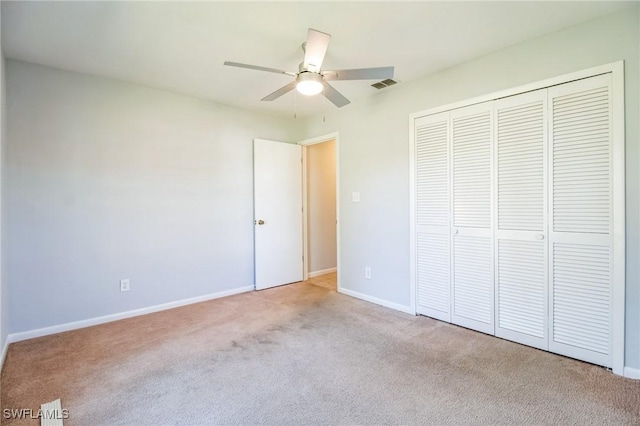 unfurnished bedroom featuring ceiling fan, a closet, and light carpet