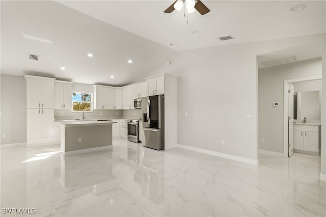 kitchen with a center island, lofted ceiling, ceiling fan, white cabinetry, and stainless steel appliances