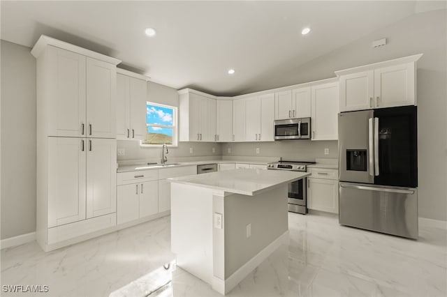 kitchen with stainless steel appliances, sink, white cabinets, a center island, and lofted ceiling