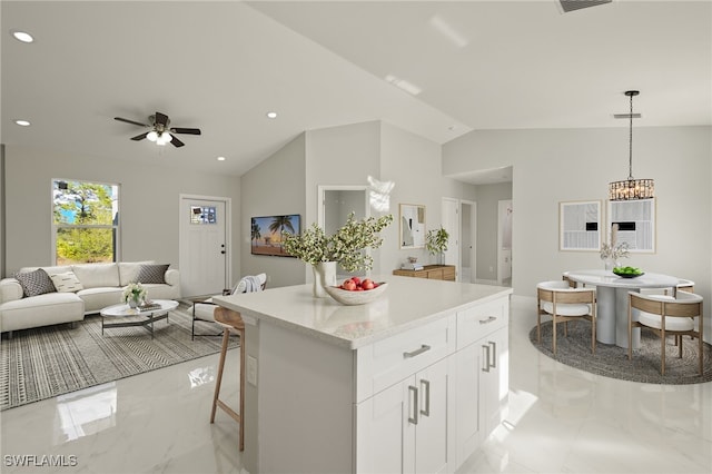 kitchen featuring a breakfast bar, ceiling fan, decorative light fixtures, white cabinetry, and lofted ceiling