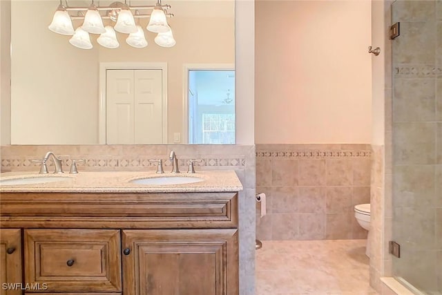 bathroom with vanity, tile patterned floors, toilet, tile walls, and a shower with shower door