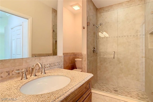 bathroom featuring vanity, toilet, an enclosed shower, and tile walls