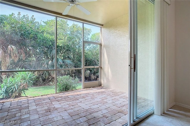 unfurnished sunroom with ceiling fan