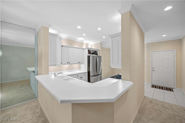 kitchen featuring kitchen peninsula, stainless steel fridge, light colored carpet, and white cabinetry