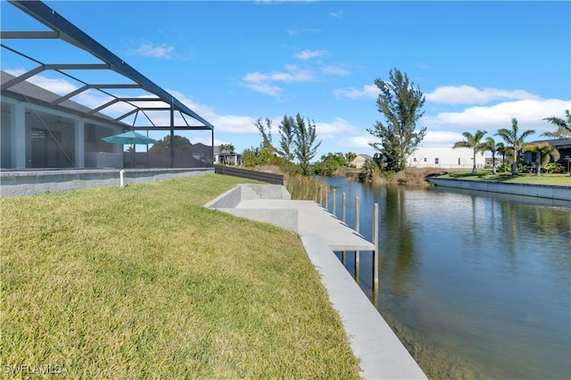 view of dock with a lanai, a water view, and a lawn