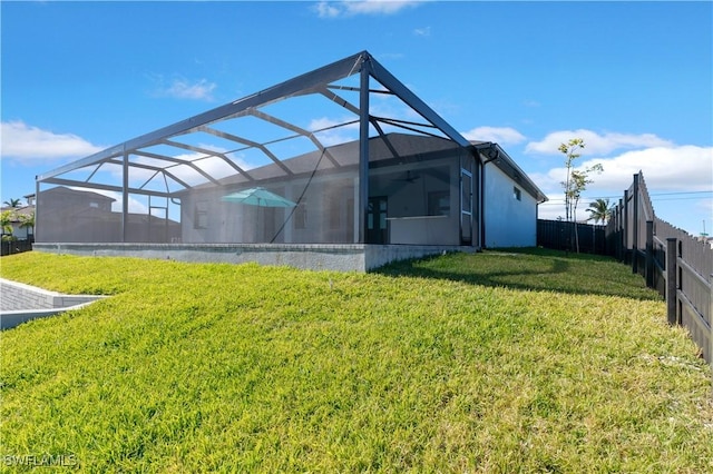 rear view of property with a lanai and a lawn