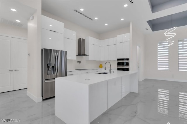 kitchen featuring white cabinets, stainless steel appliances, wall chimney range hood, and sink