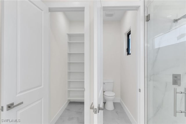 bathroom featuring toilet and a shower with door